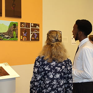 Loverte Larkai '18 (r) shows his senior art project at Showcase 2018