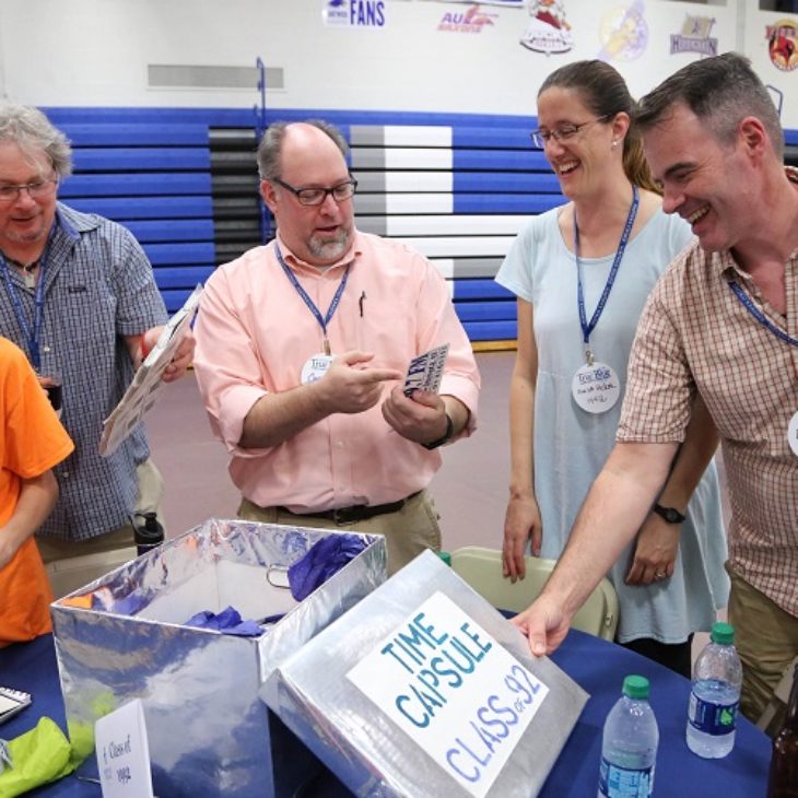 Alumni opening up class time capsule during True Blue Weekend