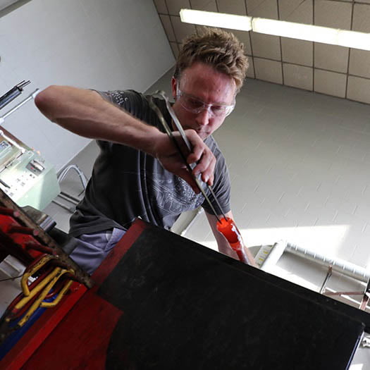 Art alumnus working in glass blowing studio
