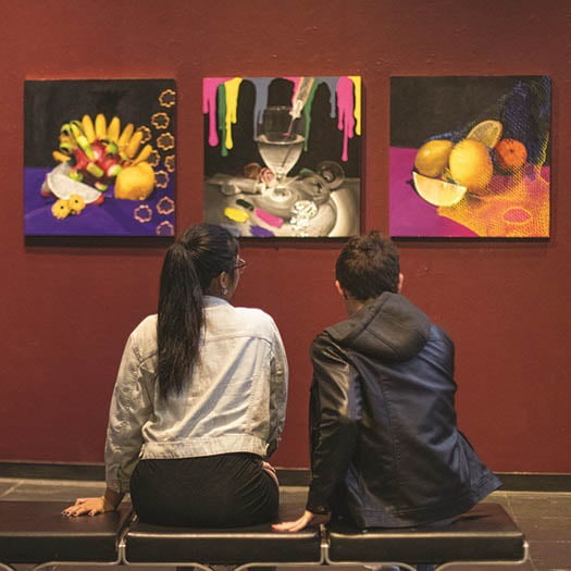 Hartwick College students sitting viewing paintings during exhibition