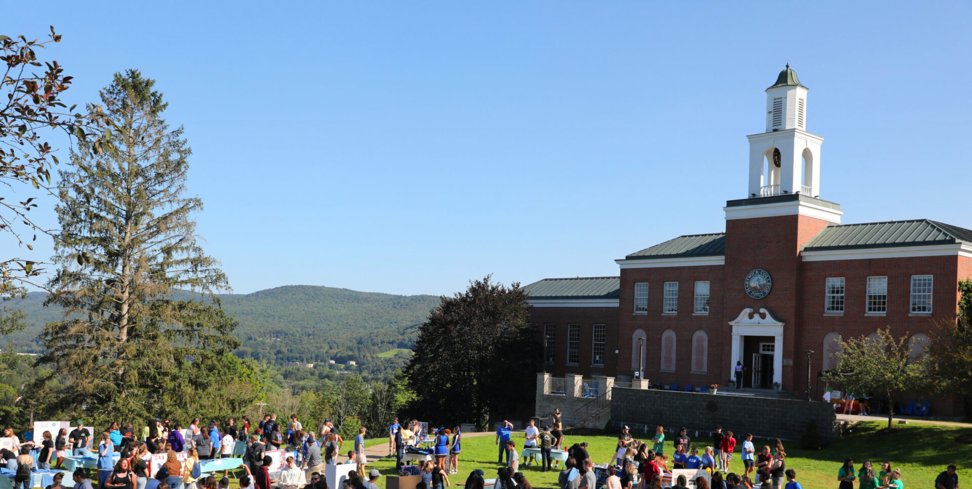 Hartwick College Frisbee Field crowded with students during club fair with Yager Hall in the background