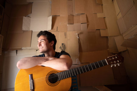 Hartwick student with guitar sitting inside Box City House