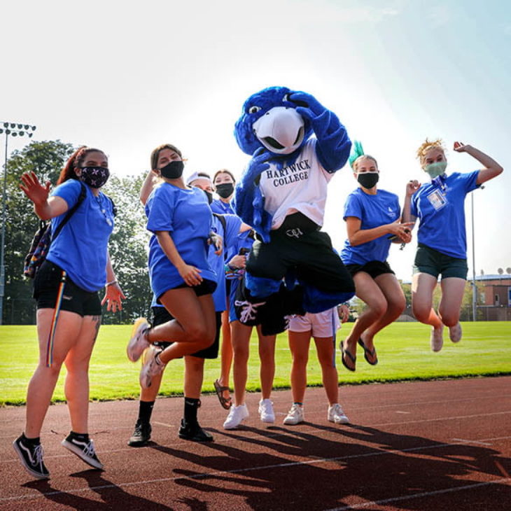 Hartwick College students jumping with Swoop, the mascot