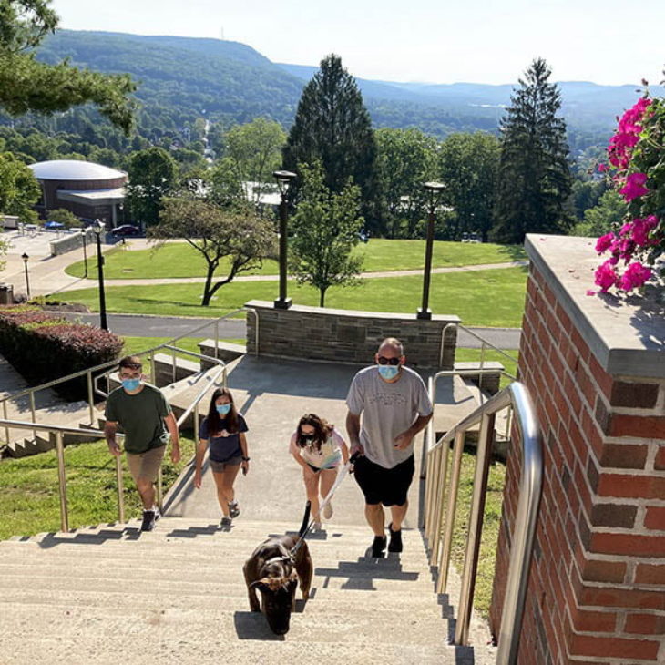 Hartwick College students and families climbing Memorial Staircase from Frisbee Field, valley view in background