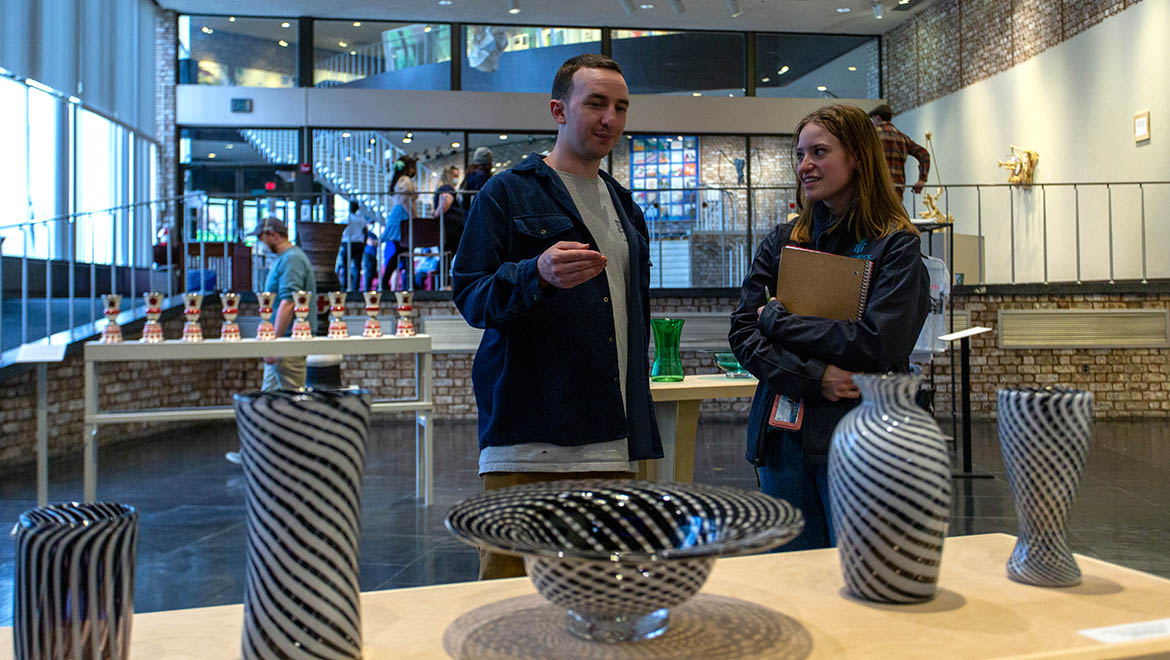 Hartwick College students in Foreman Gallery during Student Showcase discussing student blown glass work
