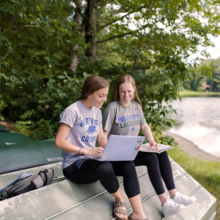 Hartwick students with computer by lake