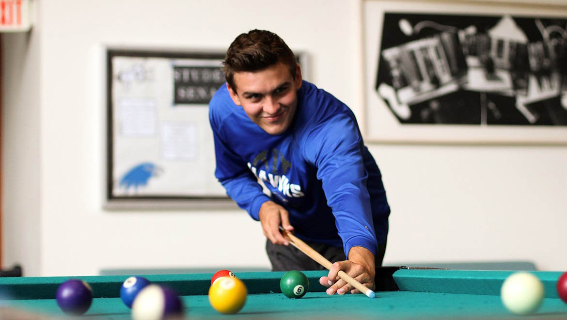 Student playing pool in Stack Lounge