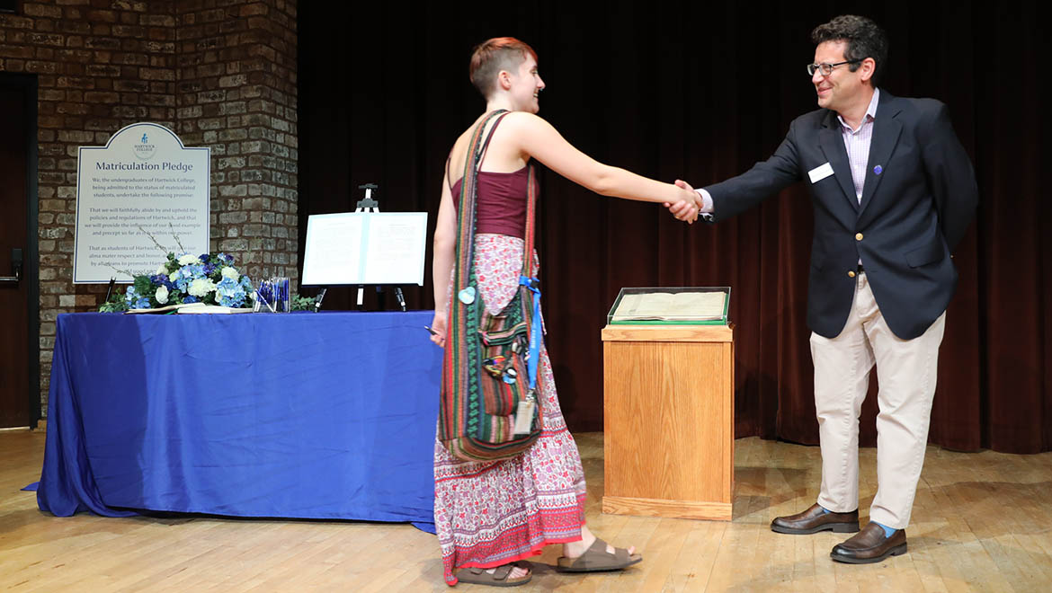 New Hartwick student shaking hands with President Reisberg after signing the Matriculation Book
