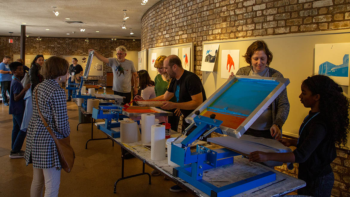 Hartwick College alumni, families and students silk screening t-shirts with Art Department faculty during Fall 2022 True Blue Weekend