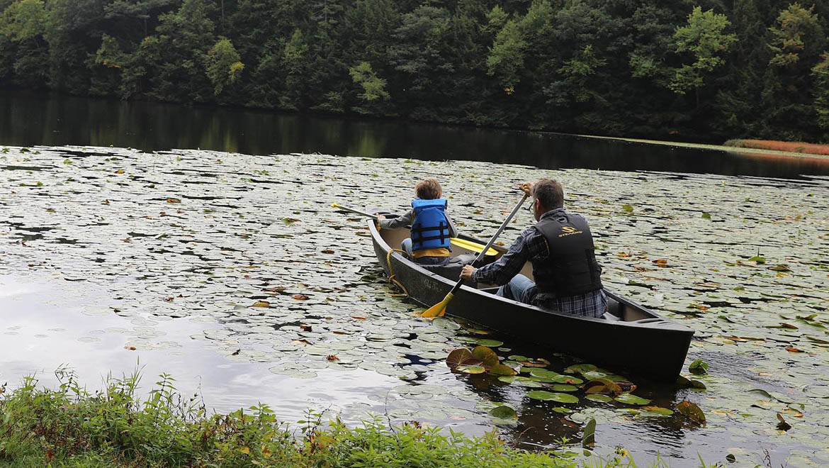 Hartwick College family in canoe at Pine Lake Environmental Campus during Fall 2022 True Blue Weekend