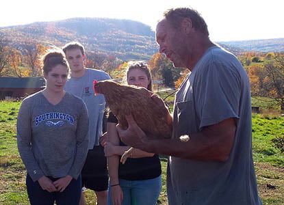 Hartwick College students with farmer learning about chickens