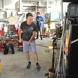 Hartwick College alumnus blowing glass in the studio of Anderson Center for the Arts