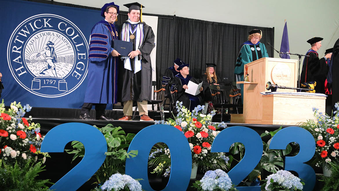 President Darren Reisberg poses with graduate upon presenting him with his degree during Hartwick College's 91st Commencement ceremony
