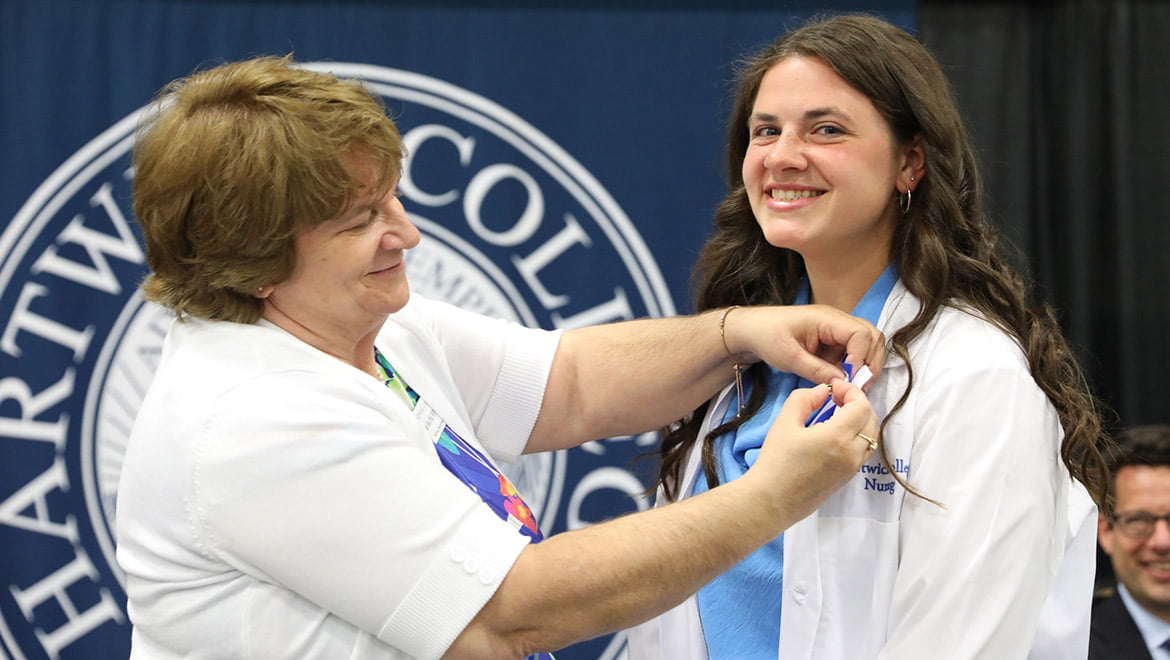 Dr. Melody Best pinning Hartwick College nursing graduate