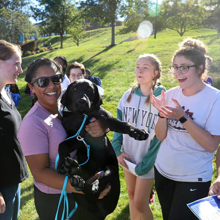 Hartwick College students on Frisbee Field with Guiding Eyes for the Blind puppy in training