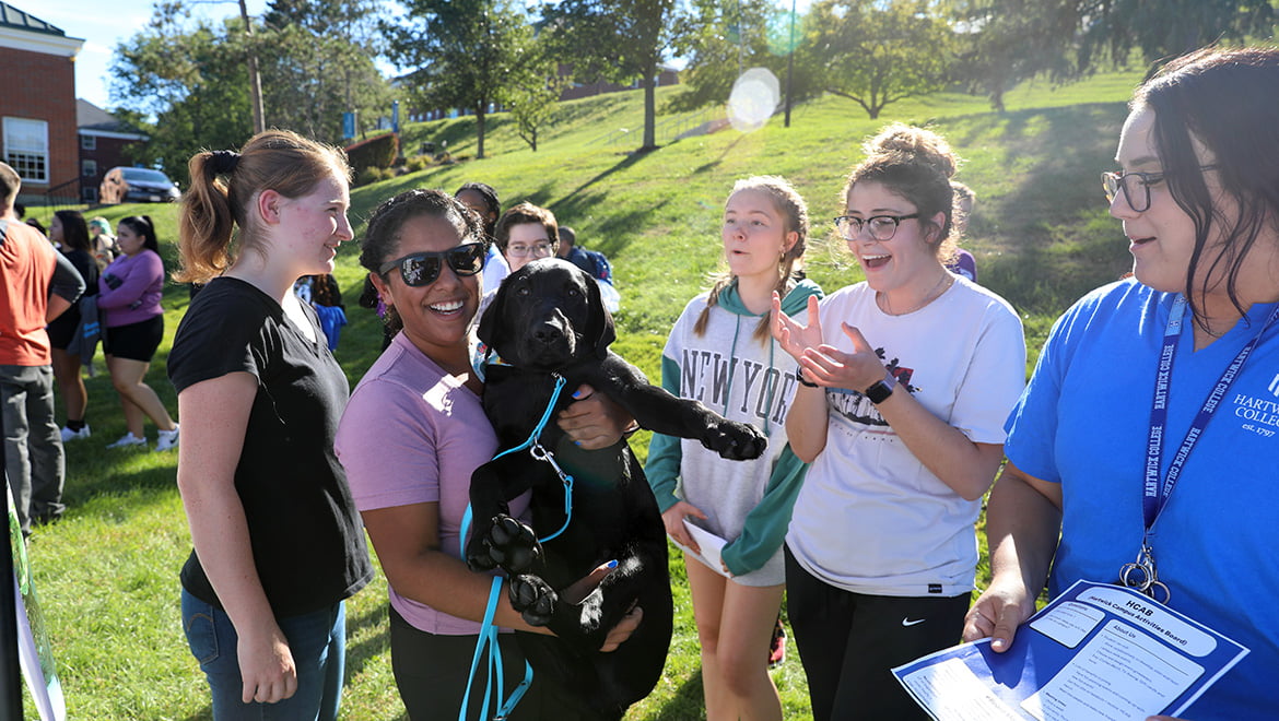 Hartwick College students on Frisbee Field with Guiding Eyes for the Blind puppy in training