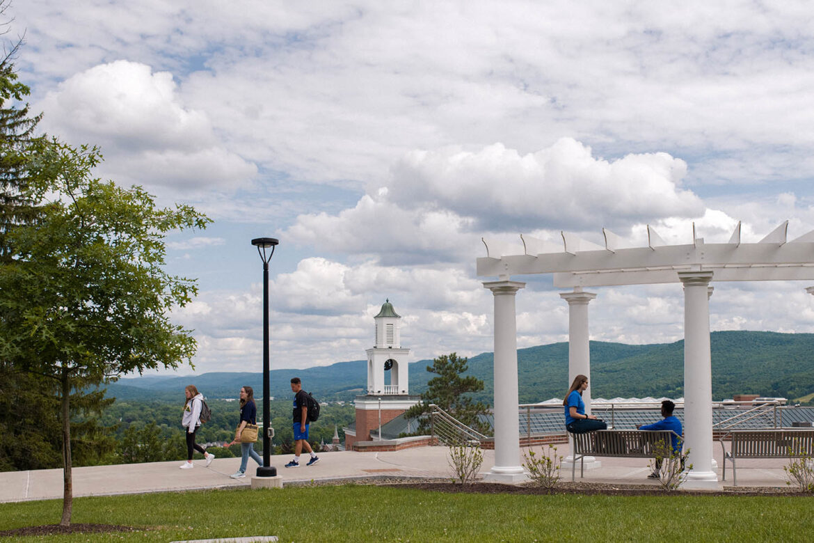 Hartwick students walking along Founders' Way with Yager Hall belltower in the view of the Susquehanna River Valley