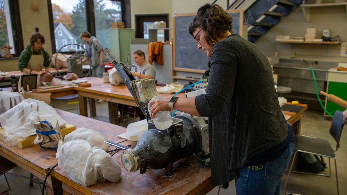 Hartwick College Professor of Art and Art History Stephanie Rozene loading clay and water into pugmill for recycling