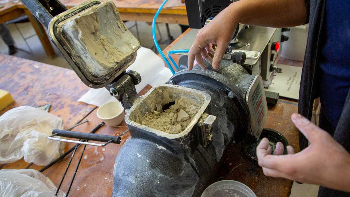 Hartwick College Professor of Art and Art History Stephanie Rozene loading clay and water into pugmill for recycling
