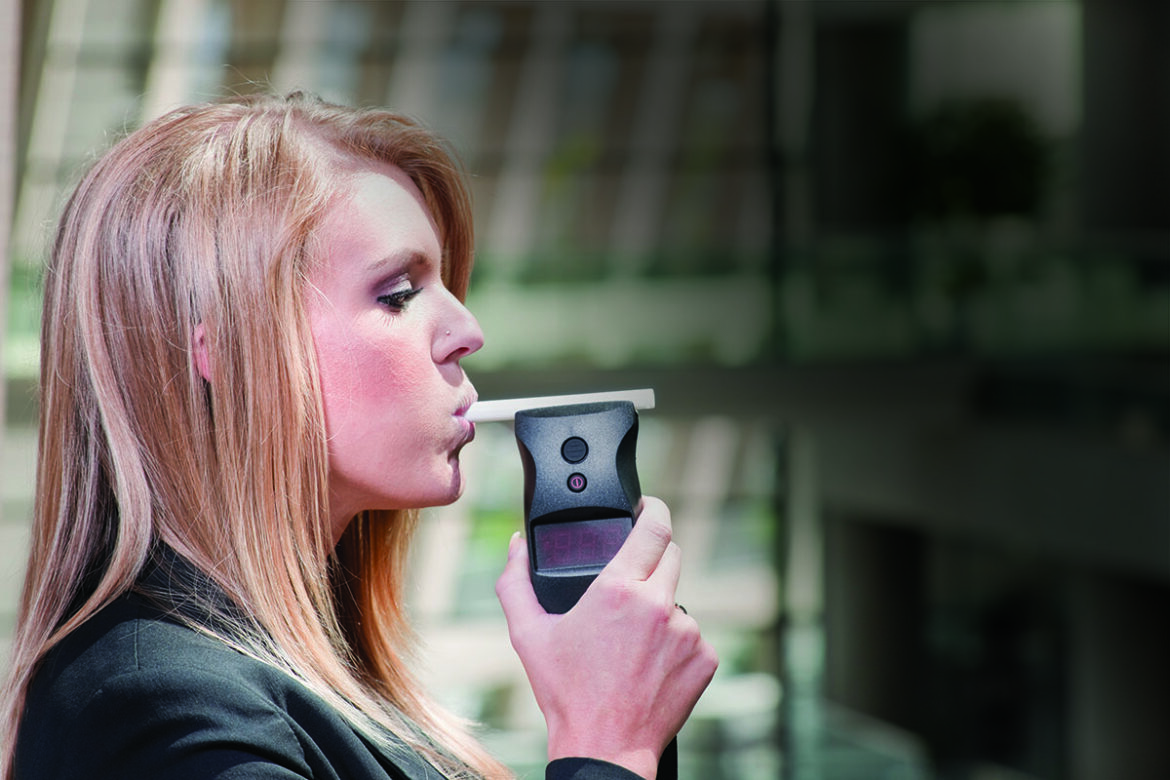 Woman using a breath alcohol testing device