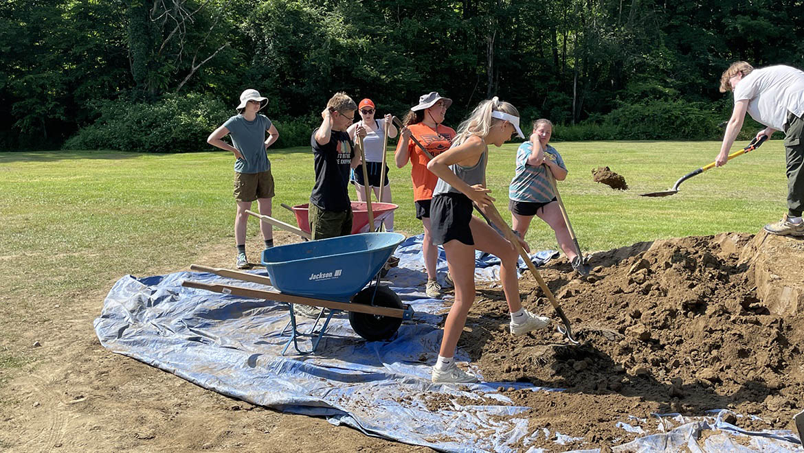 Field Archaeology student shoveling dirt at excavation site at Hartwick College's Pine Lake Environmental Campus dig