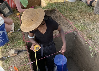 Field Archaeology student measuring excavation site at Hartwick College's Pine Lake Environmental Campus dig