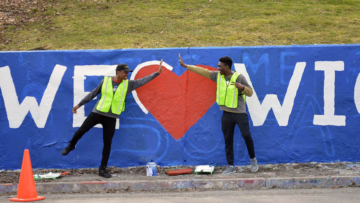 Hartwick College students painting the Wall at West Street with We Love Wick message