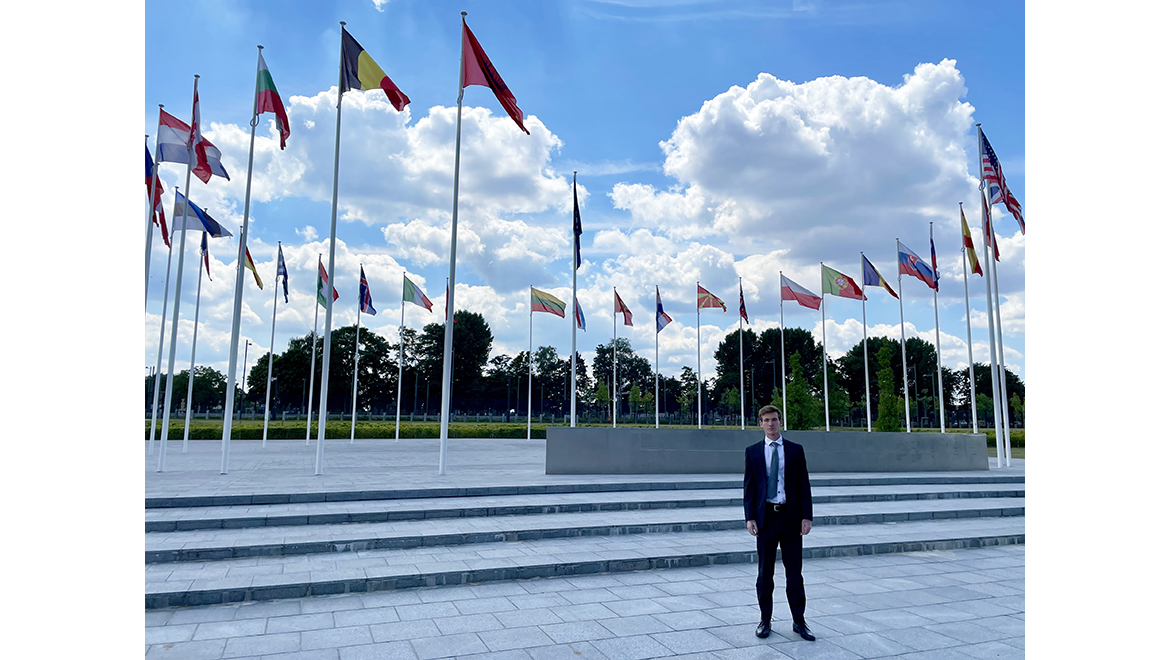 Tyler Osterhout '24 outside NATO headquarters surrounded by nation member flags