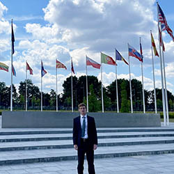 Tyler Osterhout '24 outside NATO headquarters surrounded by nation member flags