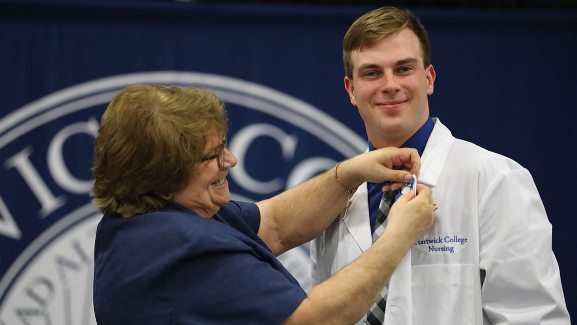 Hartwick College nursing graduate with faculty Melody Best upon receiving her nursing pin