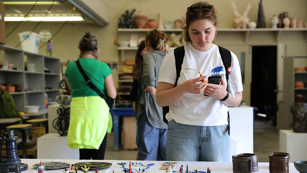 Hartwick student looking at clay pieces during Clay Club sale and demonstration, Student Showcase