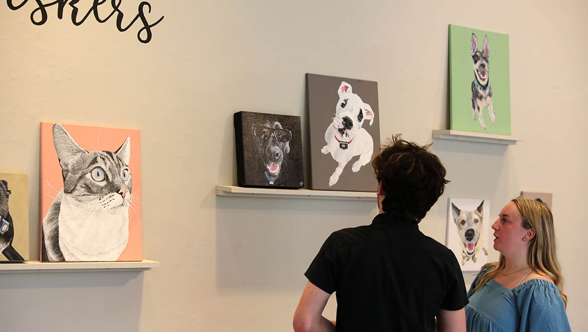 Hartwick students looking at student painting at Senior Exhibition during Student Showcase