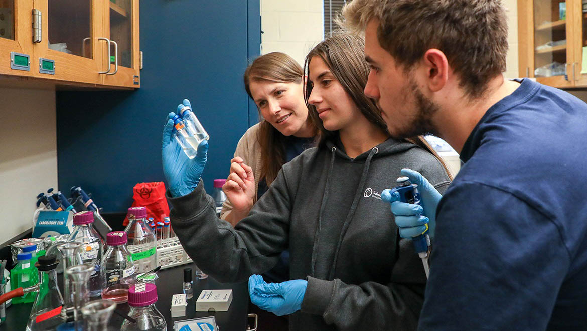 Hartwick College biology students with faculty mentor studying microbiological samples in lab