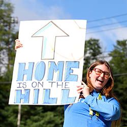 Hartwick College residential life staff member with welcome sign for new students