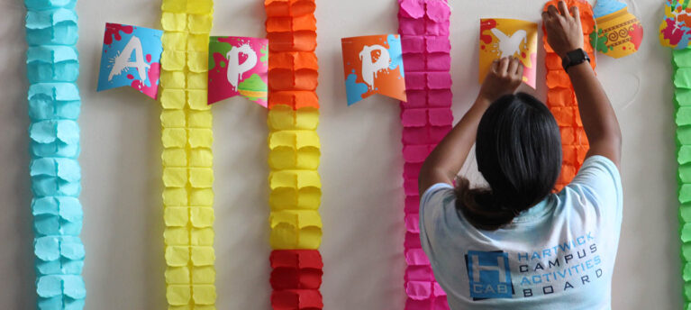 Hartwick College student hanging decorations for Holi celebrations
