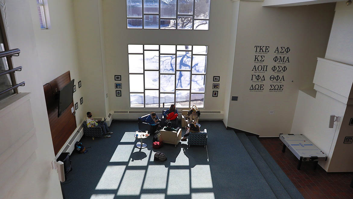 Hartwick College students studying in Stack Lounge, Dewar Union in front of large windows overlooking Frisbee Field and Yager Hall