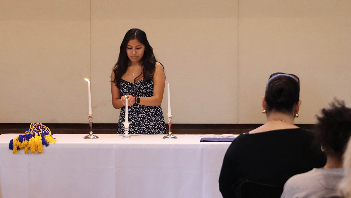 Hartwick College student lighting candle as part of Delta Alpha Pi Induction ceremony April 2025