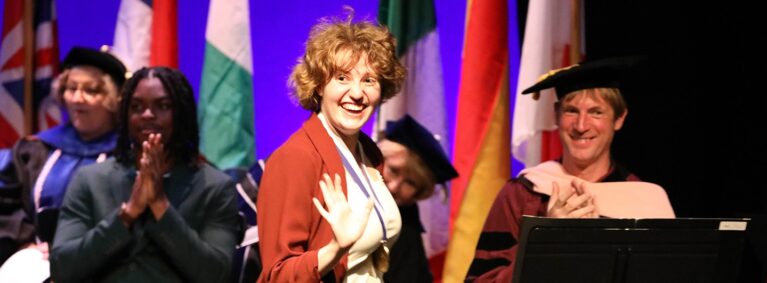 Hartwick College student receiving honors at Honors Convocation waves to crowd