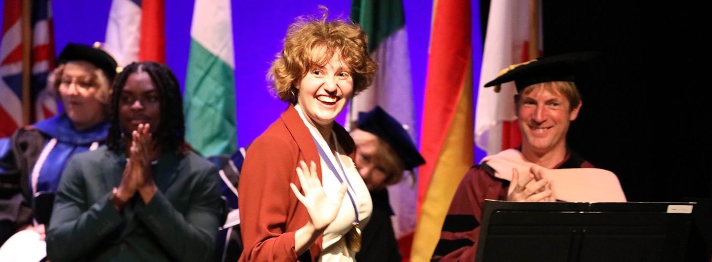 Hartwick College student receiving honors at Honors Convocation waves to crowd
