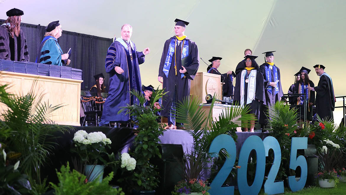 Hartwick College graduates walking across stage to receive their diplomas