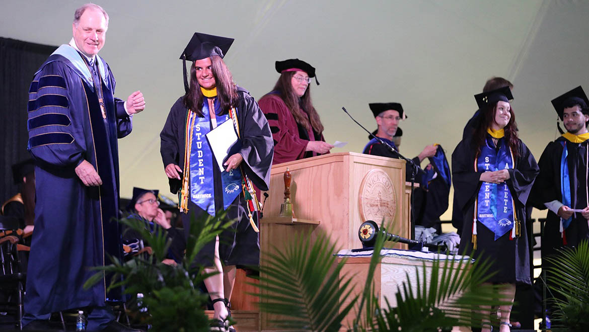 Hartwick College graduates walking across stage to receive their diplomas