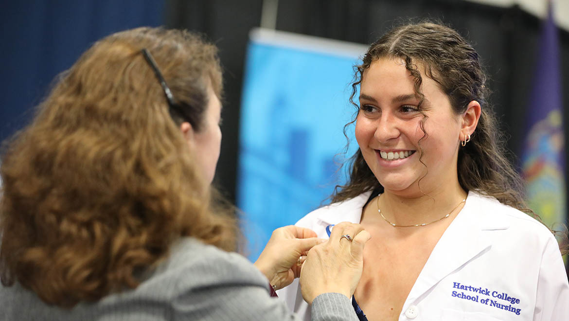 Hartwick College nursing graduate being pinned by faculty member