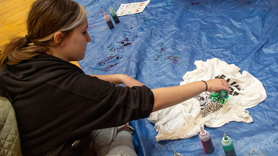 Hartwick College student tie dying t-shirt at Pine Lake craft event