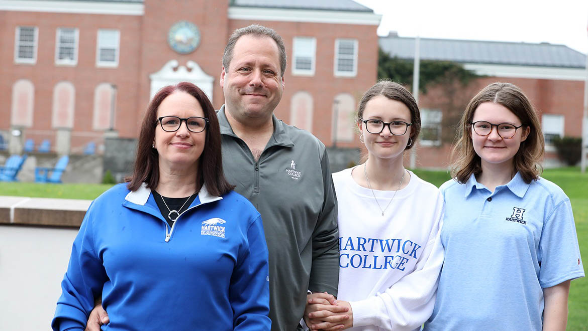 Hartwick College alumni Brett Schilkraut ’95 and Danielle Quilligan ’99 with daughters Taylor and Kaitlyn with Yager Hall in background