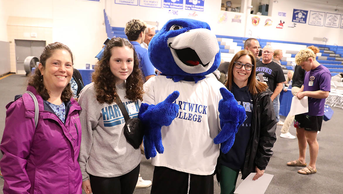 New Hartwick student with family posing for photos with Swoop in Lambros Arena