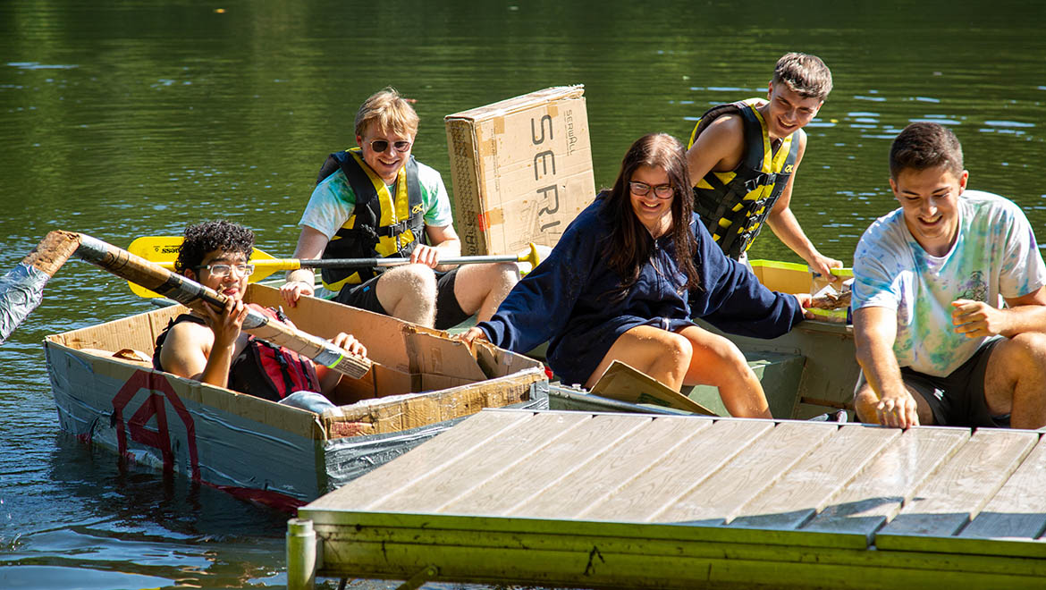 Hartwick College students at Pine Lake Cardboard Boat race during Wick Weekend