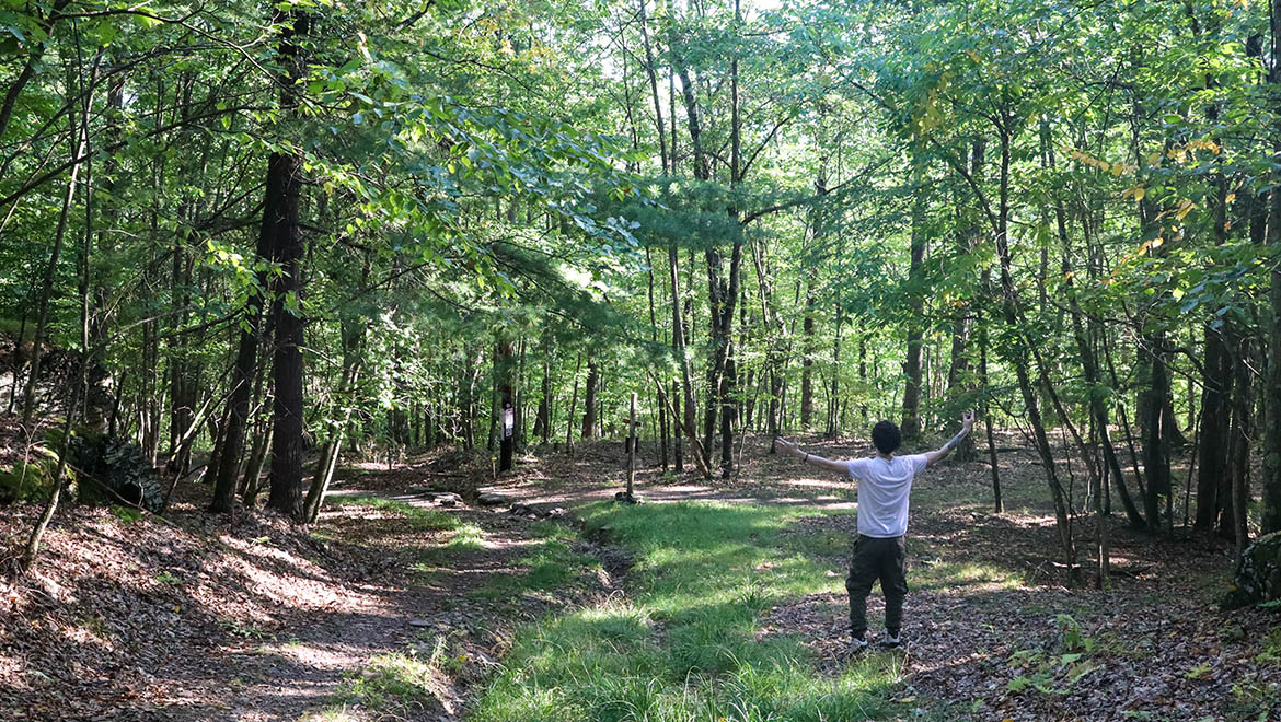 Hartwick College student along trail with forest surroundings