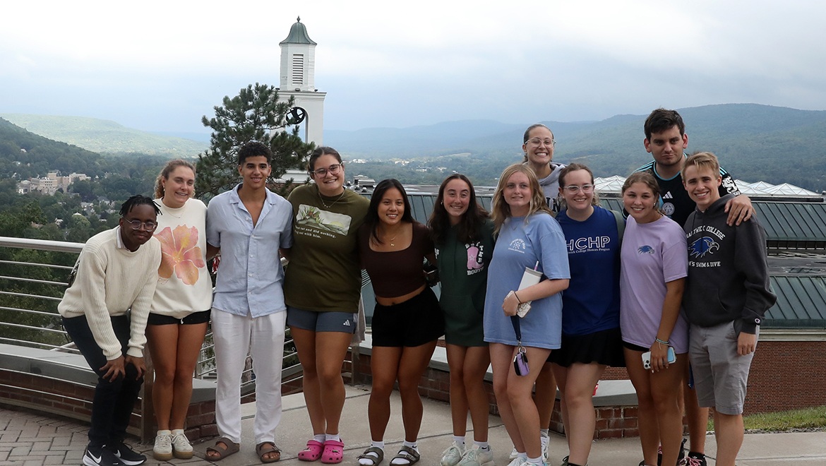 Hartwick College students on Founders' Way with Yager Hall Bell Tower and valley view in the background