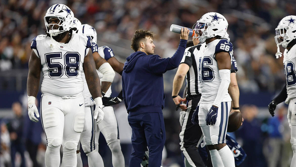 Nate Benjamin offering water to Dallas Cowboy players on the field during a game
