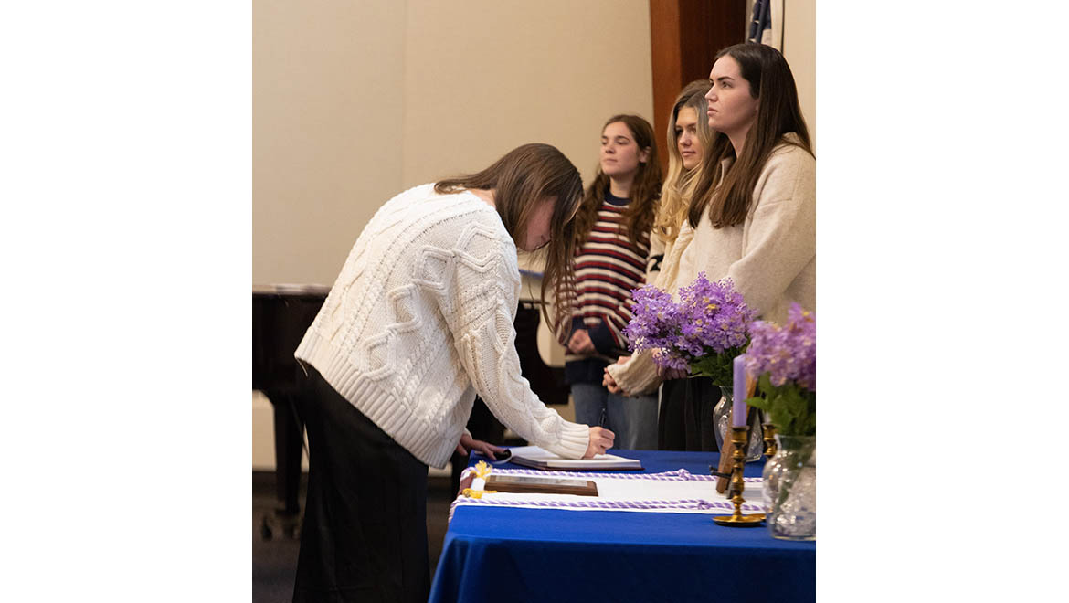 Hartwick College nursing student signing honor society chapter book during Sigma Theta Tau International Honor Society induction ceremony